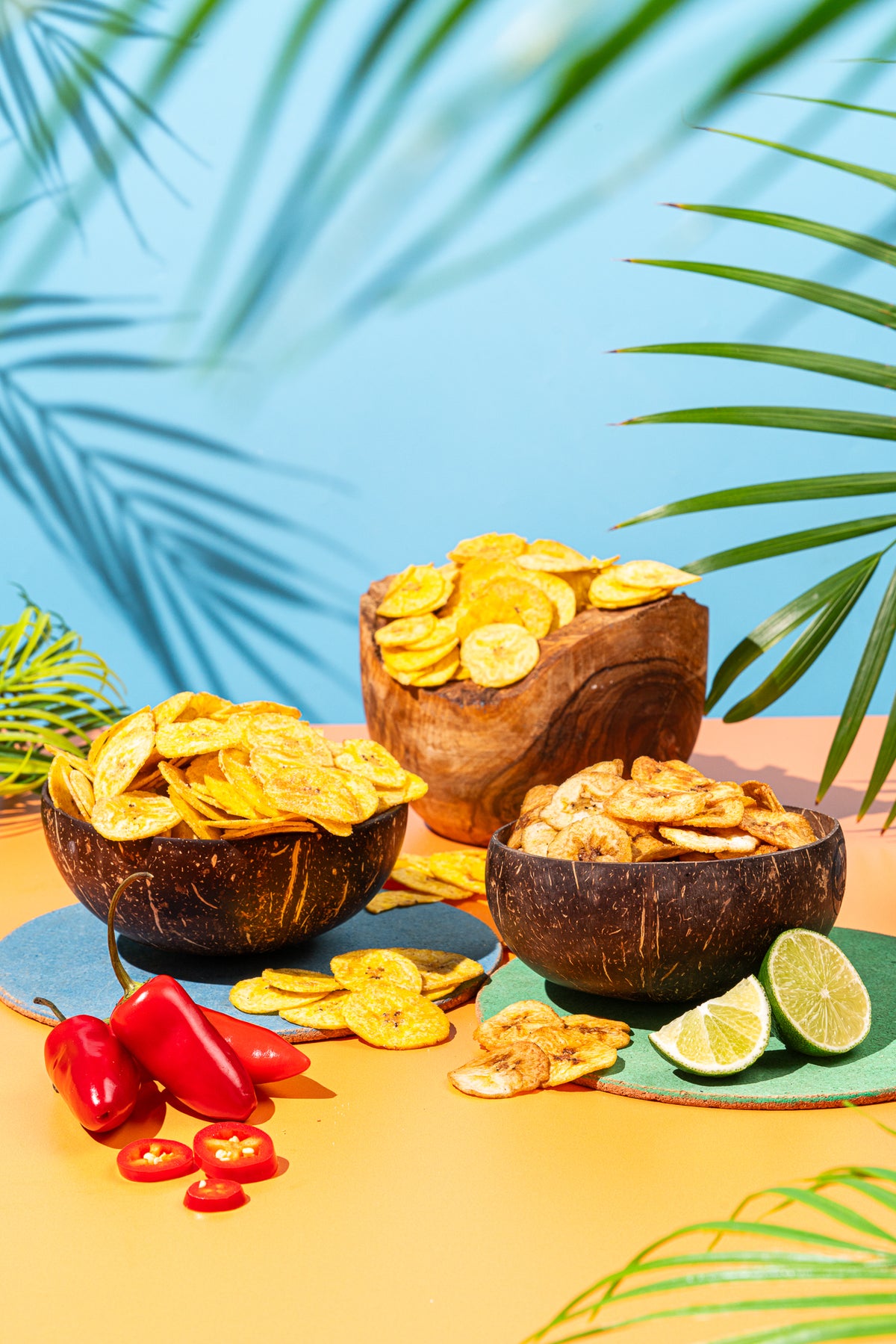 Three bowls of plantain chips with chillies and lime